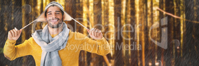 Composite image of portrait of smiling man holding wooly hat