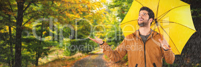 Composite image of full length of young man holding yellow umbrella