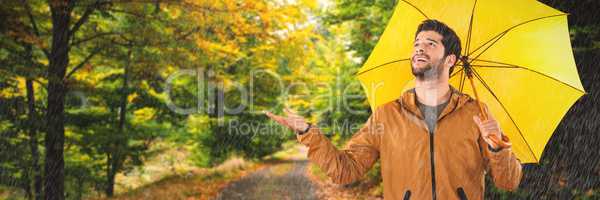 Composite image of full length of young man holding yellow umbrella