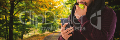 Composite image of man eating apple while using mobile phone
