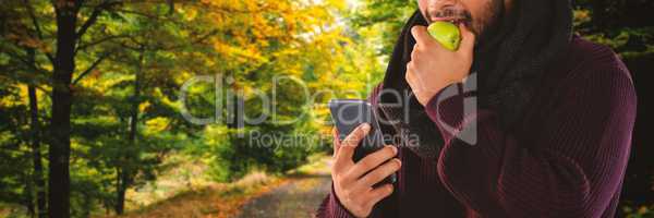 Composite image of man eating apple while using mobile phone