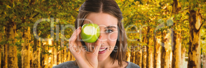 Composite image of portrait of young woman holding granny smith apple