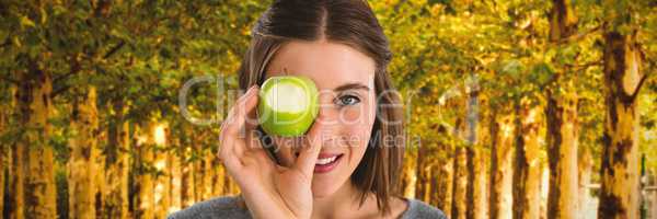 Composite image of portrait of young woman holding granny smith apple