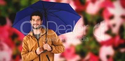 Composite image of portrait of young man holding blue umbrella