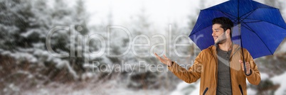 Man with blue umbrella in snow forest