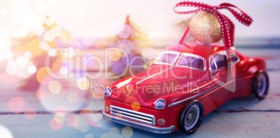 Toy car carrying christmas bauble ball on wooden plank