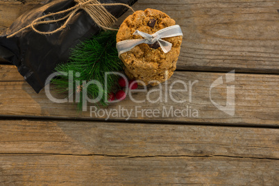 View of cookies with pine needles and cheeries by plastic bag on table