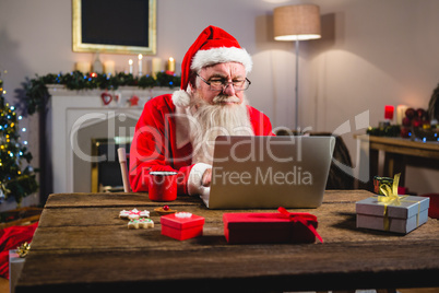 Santa Claus using laptop on table