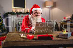 Santa Claus using laptop on table