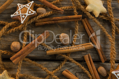 Overhead view of rope with star shape cookies and cinnamon sticks by walnuts