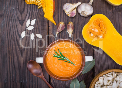 pumpkin soup in a ceramic plate with a wooden spoon