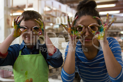 Mother and son gesturing in pottery workshop