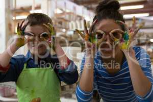 Mother and son gesturing in pottery workshop