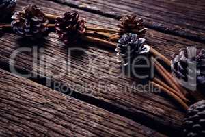 Pine cone and cinnamon sticks on wooden plank