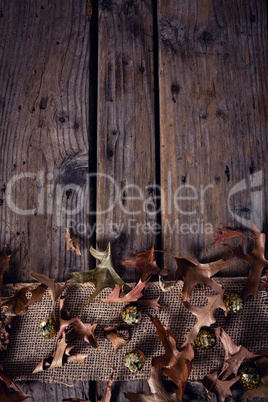 Sequin balls and dry leaves on wooden plank