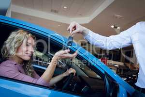 Cropped image of salesman giving keys to customer