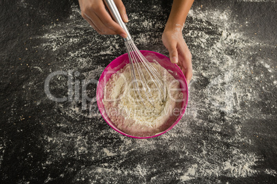 Woman whisking flour in bowl