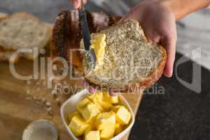 Woman applying butter over multigrain bread slice