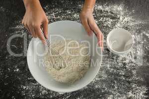 Woman whisking flour in bowl