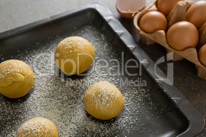 Dough balls with icing sugar on baking tray
