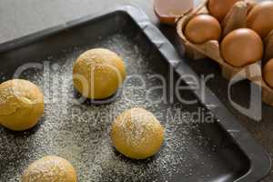 Dough balls with icing sugar on baking tray