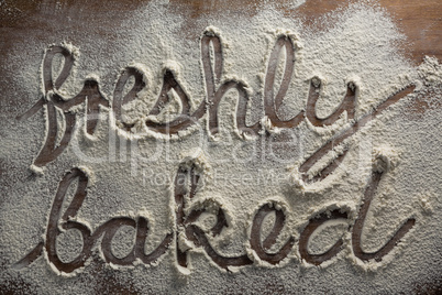 The word freshly baked written on sprinkled flour