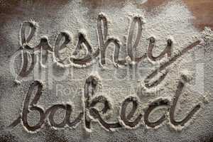 The word freshly baked written on sprinkled flour