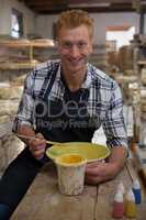 Male potter painting a bowl in pottery workshop