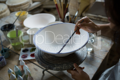 Female potter painting bowl