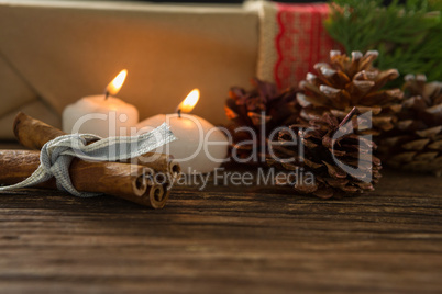Illuminated candle with pine cones and cinnamon sticks