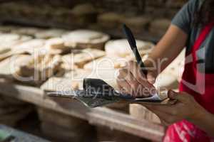Female potter writing in clipboard