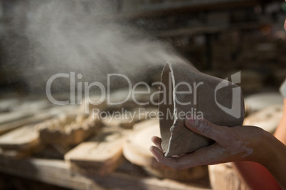 Female potter blowing dust from mud