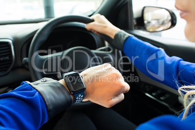 Cropped image of woman looking at smart watch during test drive