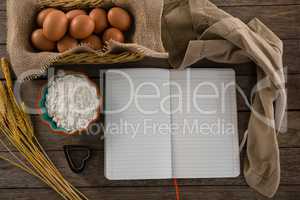 Book, eggs, flour, cookie cutter and cloth kept on a table