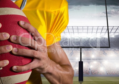 american football  player standing in stadium holding the ball