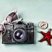 Ancient camera, compass and sea souvenirs on a blue background.