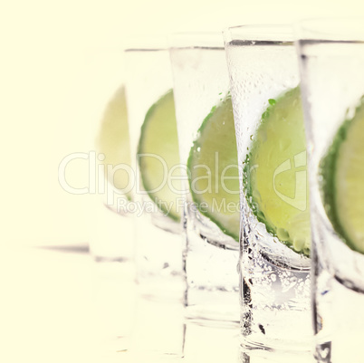 Alcoholic cocktail with lime and ice, isolated with reflection