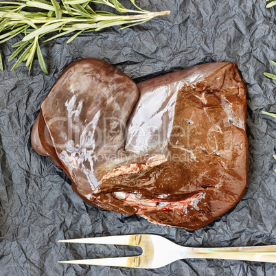 healthy fod Raw liver with rosemary on a black background