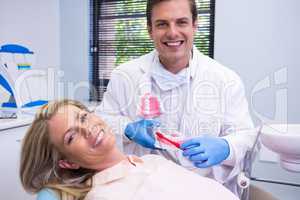 Happy dentist holding dental mould by woman at medical clinic