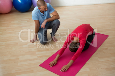 Instructor guiding student in doing child pose at yoga studio