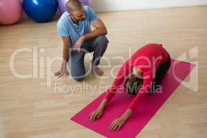 Instructor guiding student in doing child pose at yoga studio