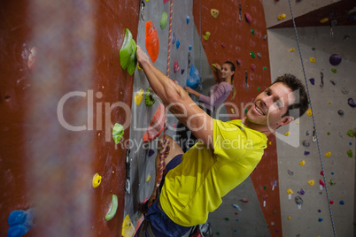 Portrait of smiling man with female athlete climbing rock