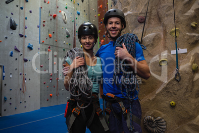 Portrait of athletes in sports helmet carrying ropes at gym