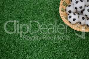 Footballs in wicker basket on artificial grass