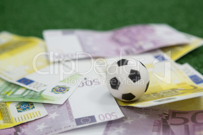 Footballs and currency notes arranged on artificial grass