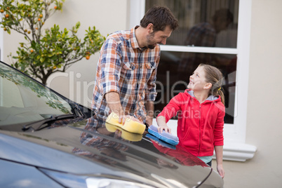 Teenage girl and father washing a car