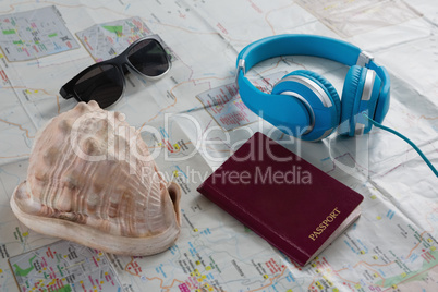 Sunglasses, headphones, passport and seashell on map