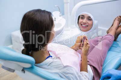 Woman looking at mirror while sitting on dentist chait at clinic