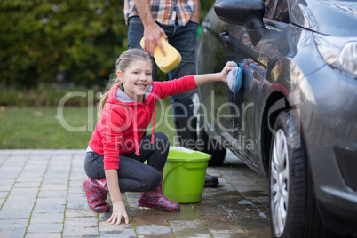 Teenage girl washing a car on a sunny day