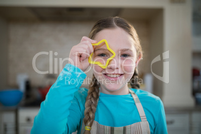 Girl holding cookie cutter on her eyes